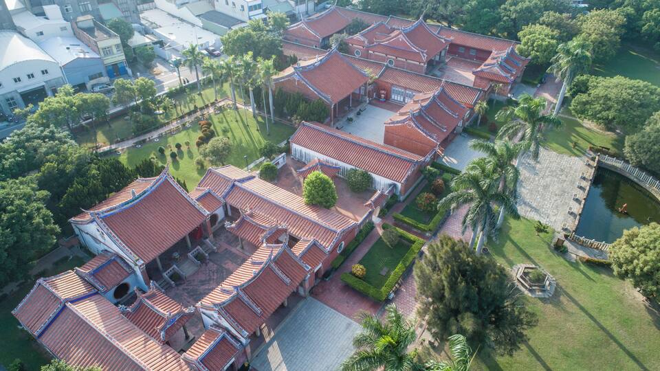An aerial view of a traditional Chinese courtyard with red-tiled roofs and lush greenery.