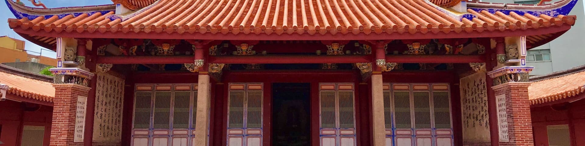 A traditional Chinese building with ornate red and blue roof tiles, a central entrance, and decorative lion statues on the roof.