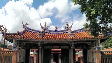 Un portón tradicional chino con tejas azules y doradas muy ornamentadas y decoraciones de dragones.