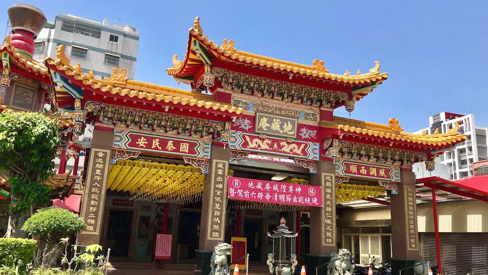 A traditional Chinese temple with ornate architecture, including red and gold decorations and statues.