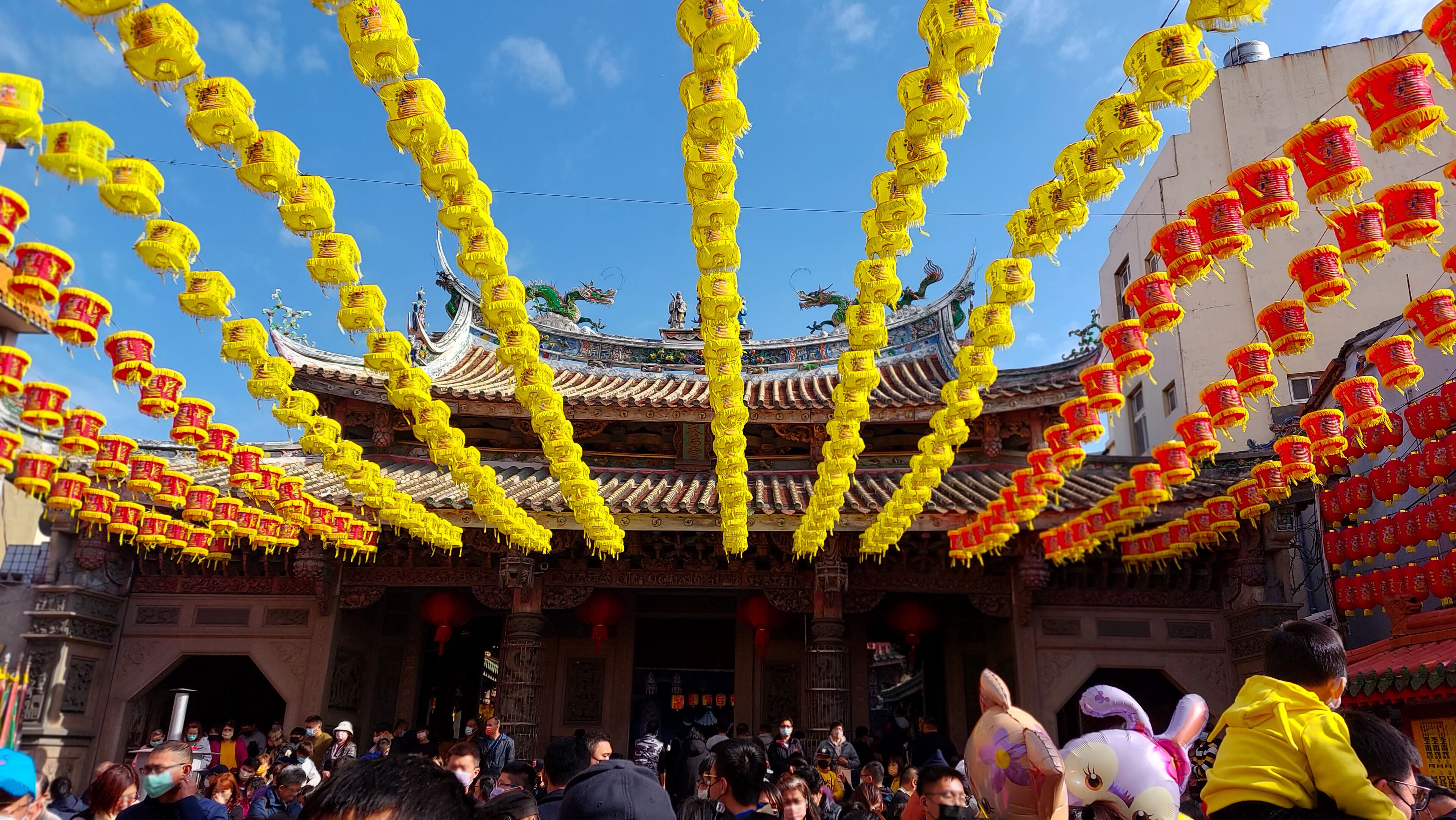 A traditional Chinese building with ornate architecture and yellow and red lanterns hanging overhead.