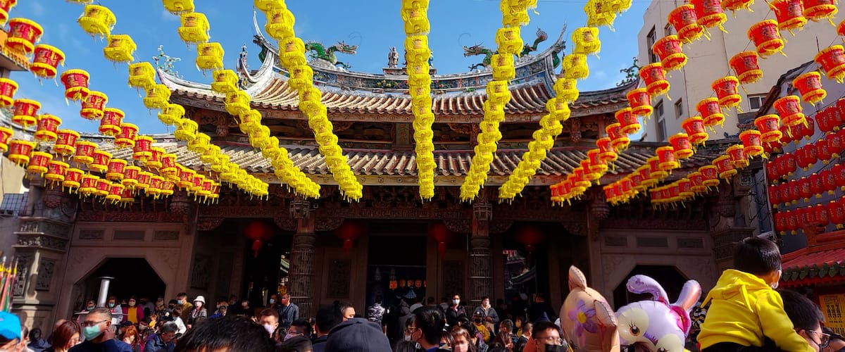 A traditional Chinese building with ornate architecture and yellow and red lanterns hanging overhead.