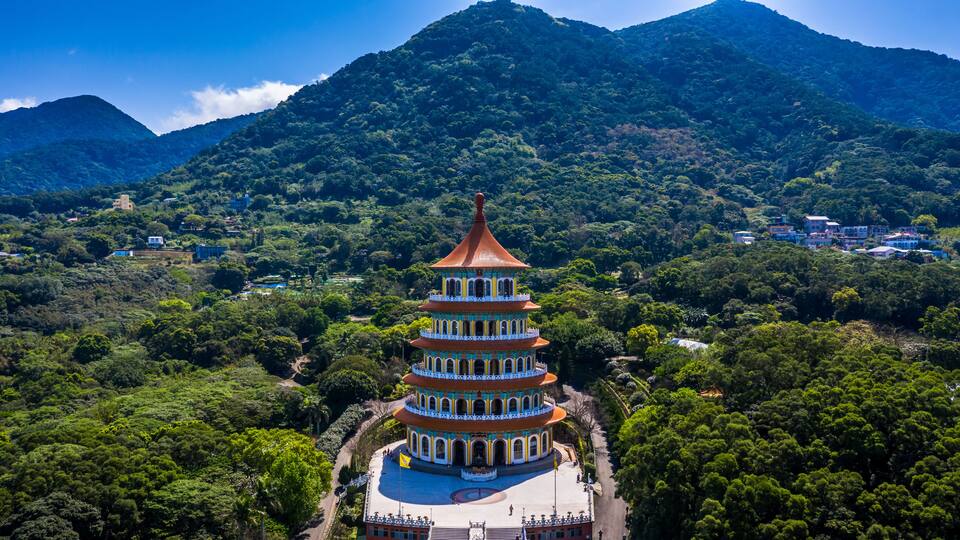 A multi-tiered pagoda surrounded by lush greenery and mountains.