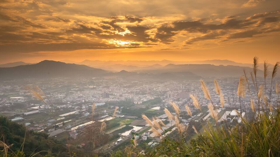 A cityscape with mountains in the background and a sunset.