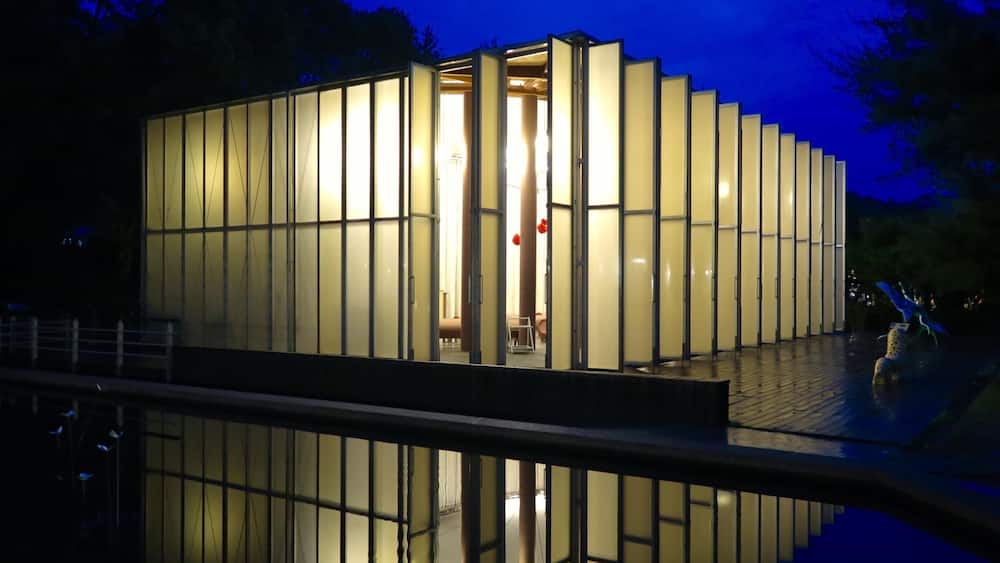 Ein modernes Gebäude mit vertikalen Glasfassaden und Spiegelungen im Wasser.