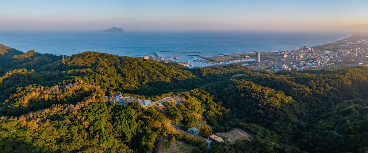 A coastal city with a mountainous backdrop and a distant island.