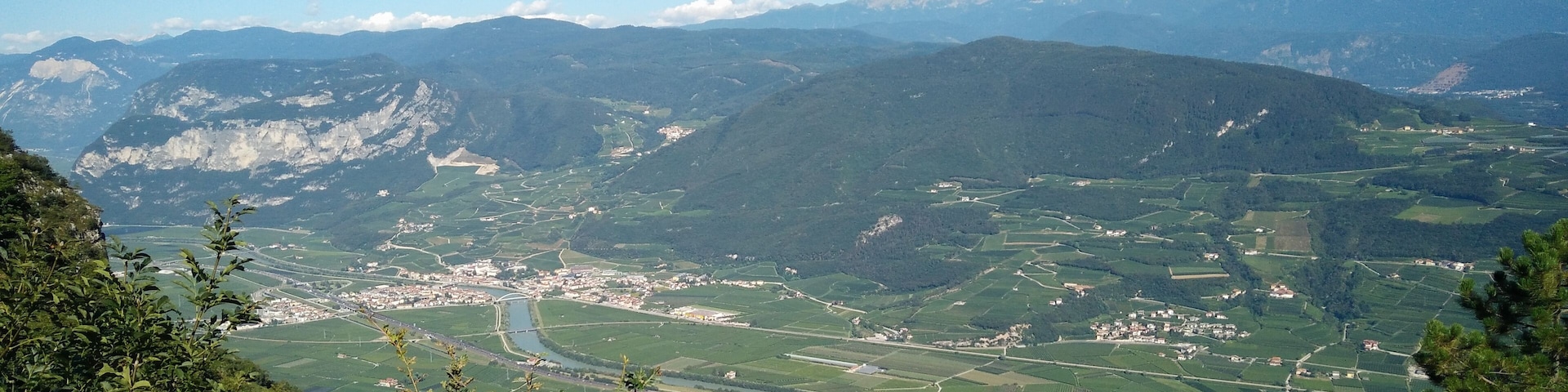 Un paisaje montañoso con un valle, un río y edificios dispersos.