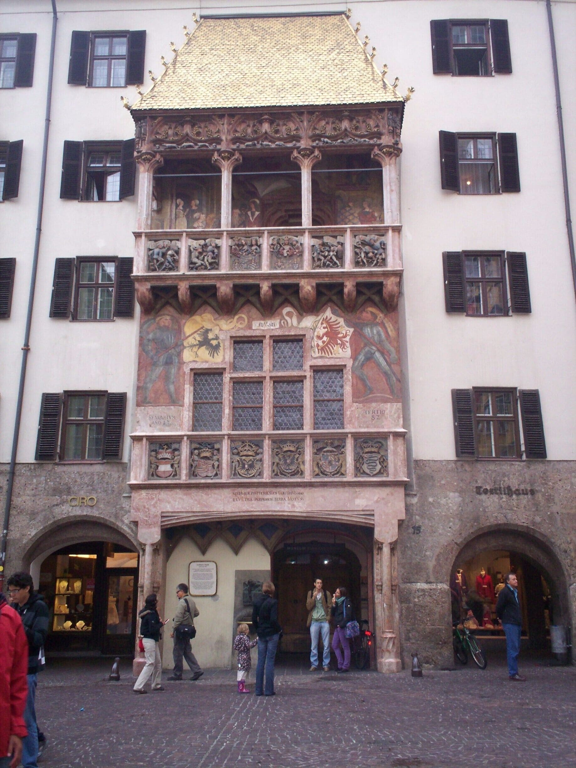 “Aprovecha cada momento y no te pierdas ni un baile, al más allá no te podrás llevar nada”
Éste es el dicho que se cuenta que figuraba en el relieve del famoso Tejadillo de Oro en el casco antiguo de Innsbruck. Se trata sólo de una suposición, porque hasta ahora, la inscripción no se ha podido descifrar con certeza – uno de los muchos secretos que envuelven al símbolo dorado de Innsbruck.
Un símbolo del antiguo centro de Europa. Un reflejo de las contradicciones en tiempo de grandes cambios. El espléndido mirador fue encargado por el emperador Maximiliano I en 1500 y está recubierto con 2.657 tejas de cobre doradas al fuego, todas ellas originales. El casco antiguo gótico de Innsbruck, que se extiende por ambos lados del Tejadillo de Oro, apenas ha cambiado desde entonces. Un paseo por sus calles permite percibir un cierto aire medieval y nos acerca a la fascinante historia de esta ciudad.