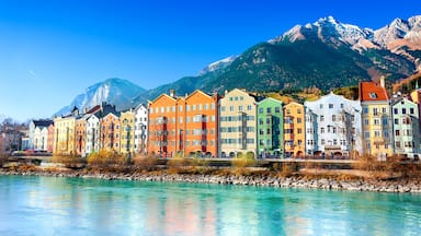 A row of colorful buildings along a river with mountains in the background.