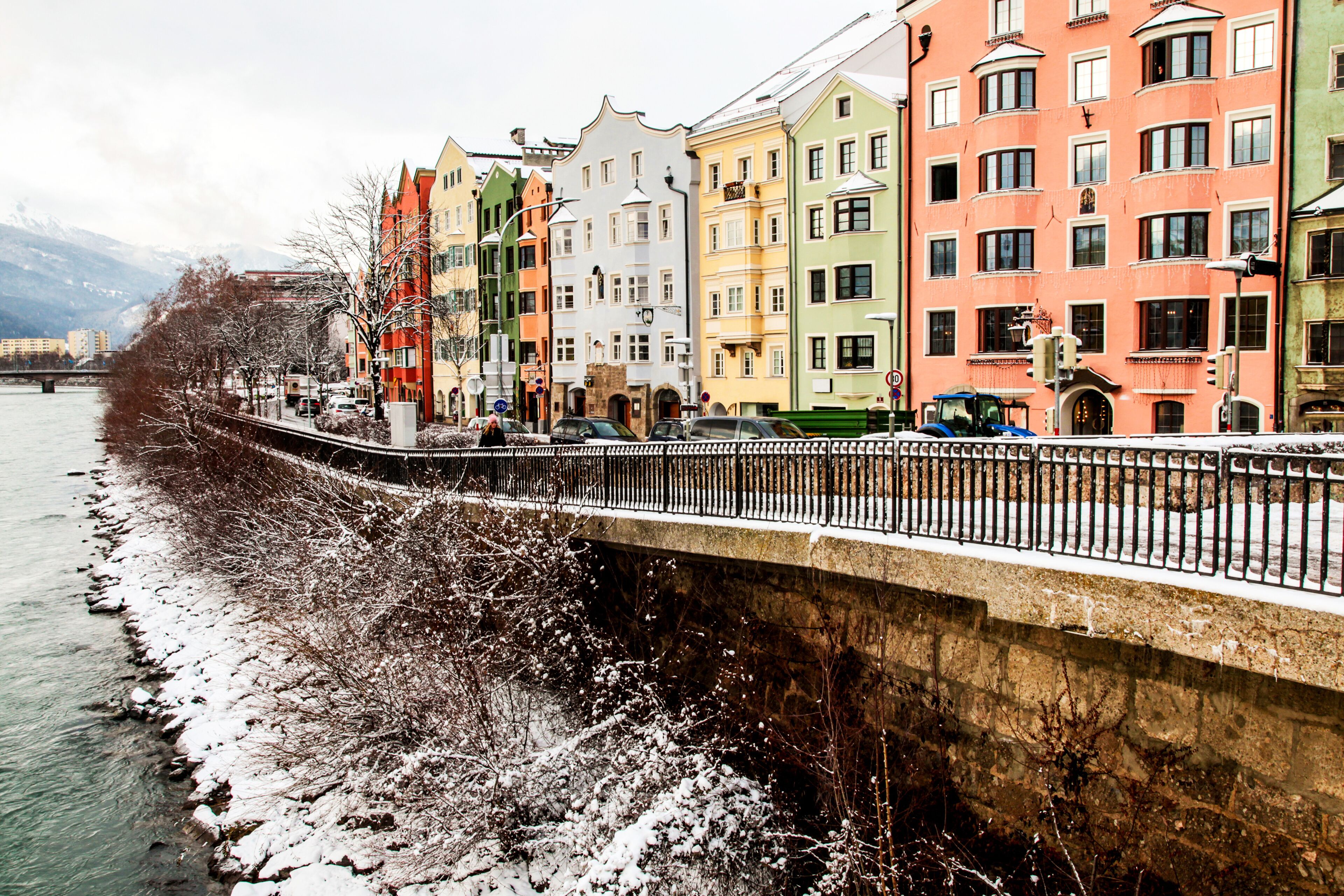 Una orilla de río cubierta de nieve con edificios coloridos y un puente.