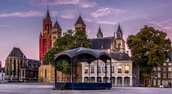 Uma praça histórica da cidade com uma igreja imponente, um campanário e um pavilhão coberto.