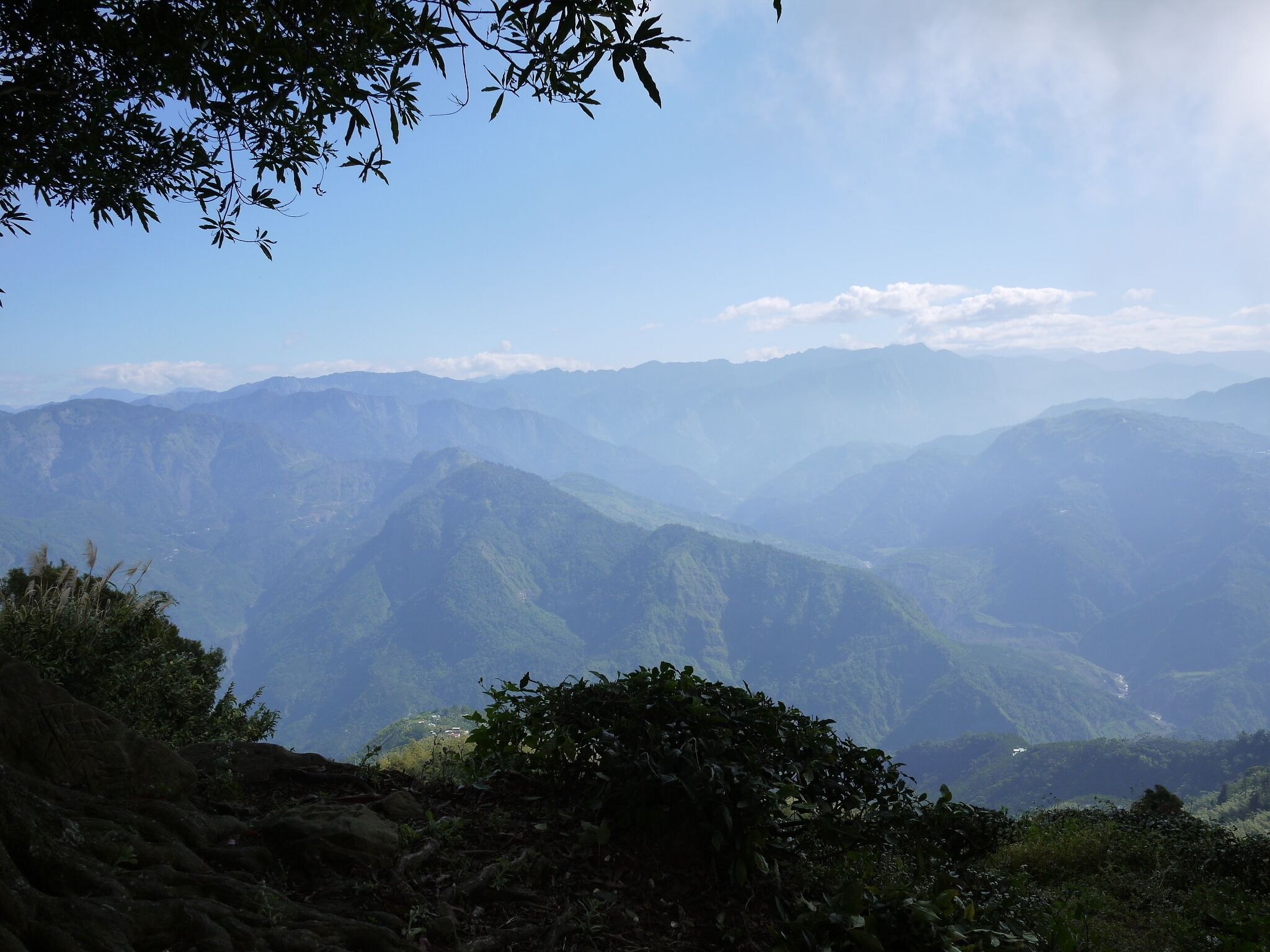Un paisaje montañoso con vegetación verde exuberante y un cielo azul despejado.