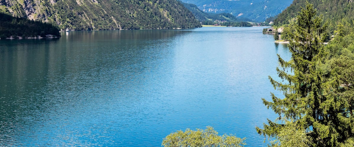 A calm lake surrounded by forested mountains.