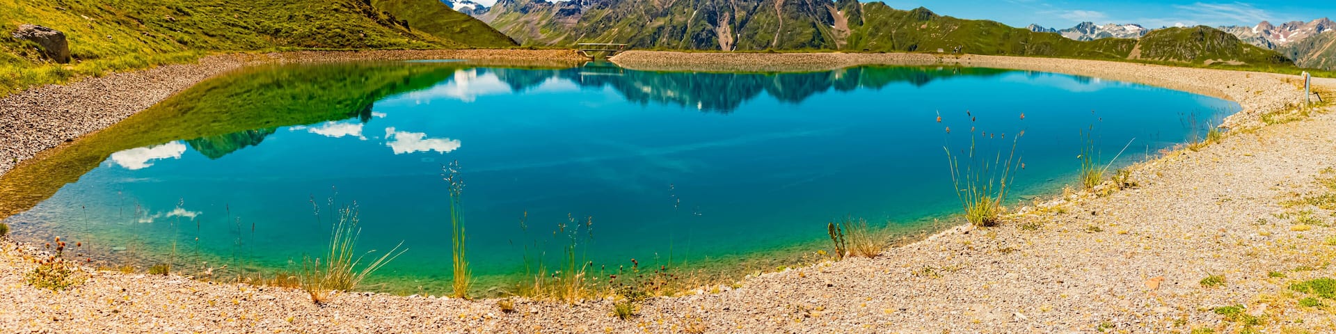 High resolution stitched alpine summer panorama with reflections in a lake at Mount Flimjoch, Ischgl, Paznaun, Silvretta, Landeck, Tyrol, Austria