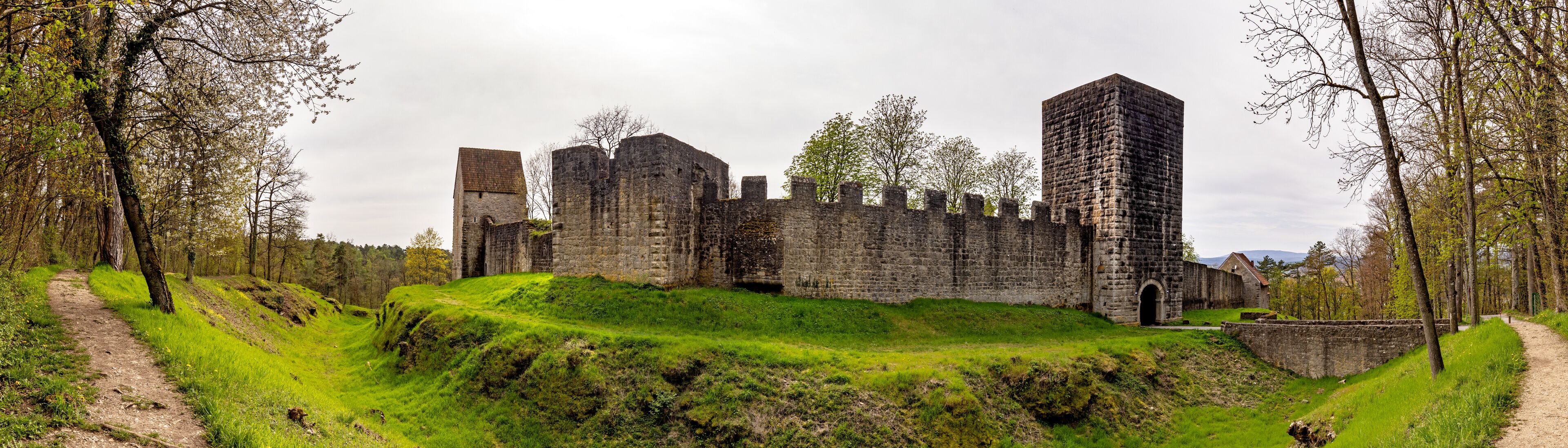 A historic stone castle surrounded by lush green hills and trees.