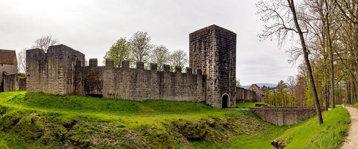 A historic stone castle surrounded by lush green hills and trees.