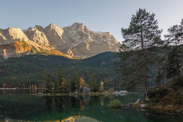 Un lac de montagne dont les eaux claires reflètent les sommets et les arbres environnants.