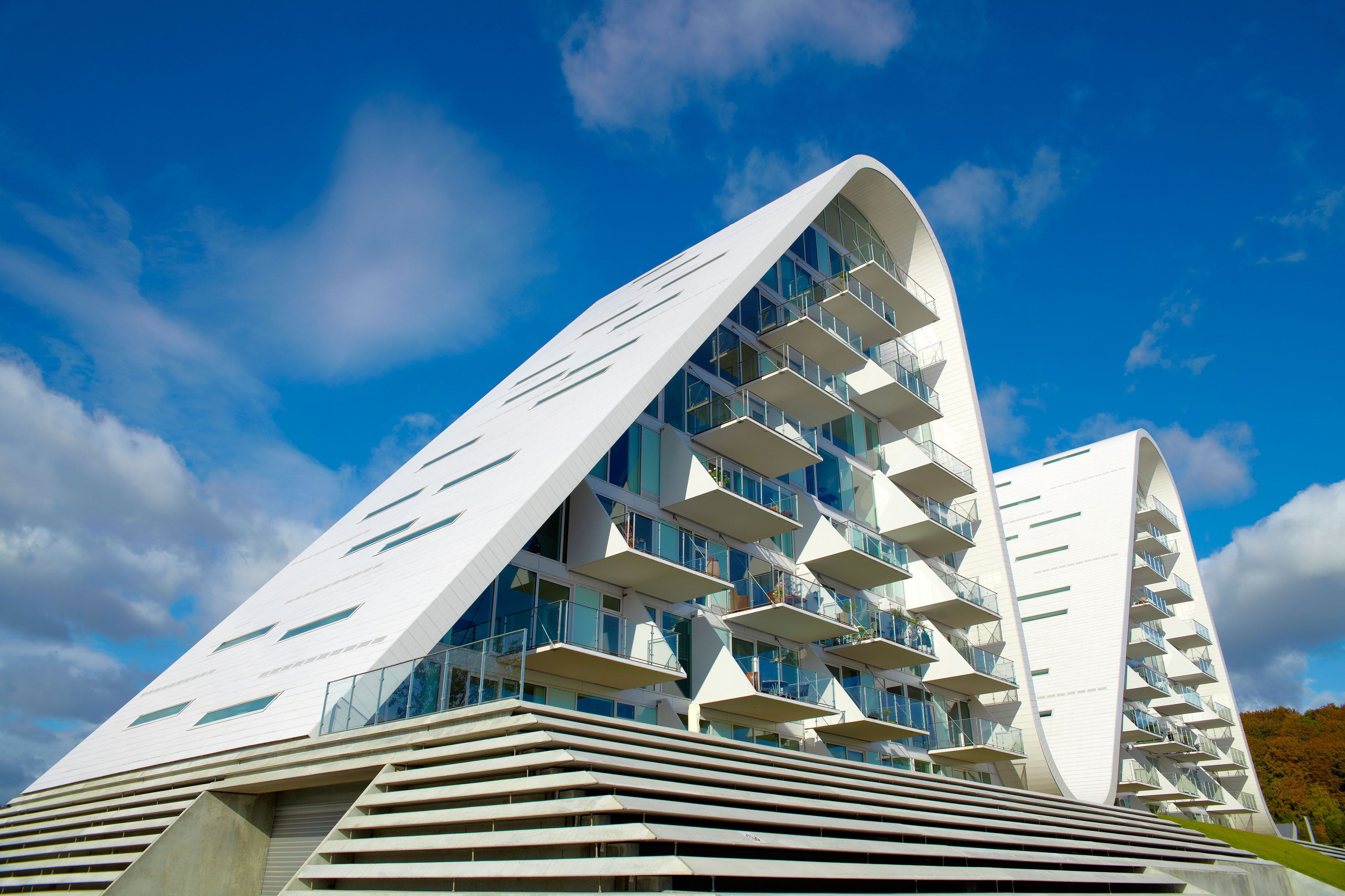 A modern architectural building with a curved facade and multiple balconies.
