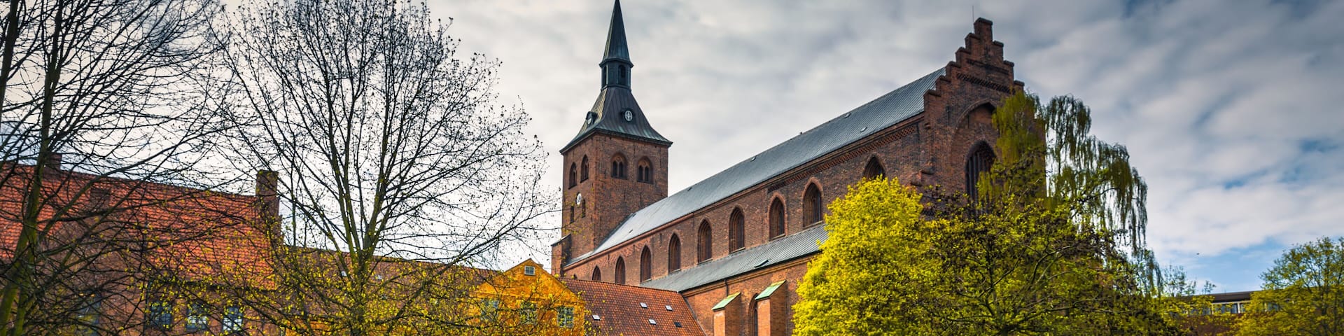 A historic church with a tall tower, a pond, and a well-maintained lawn.