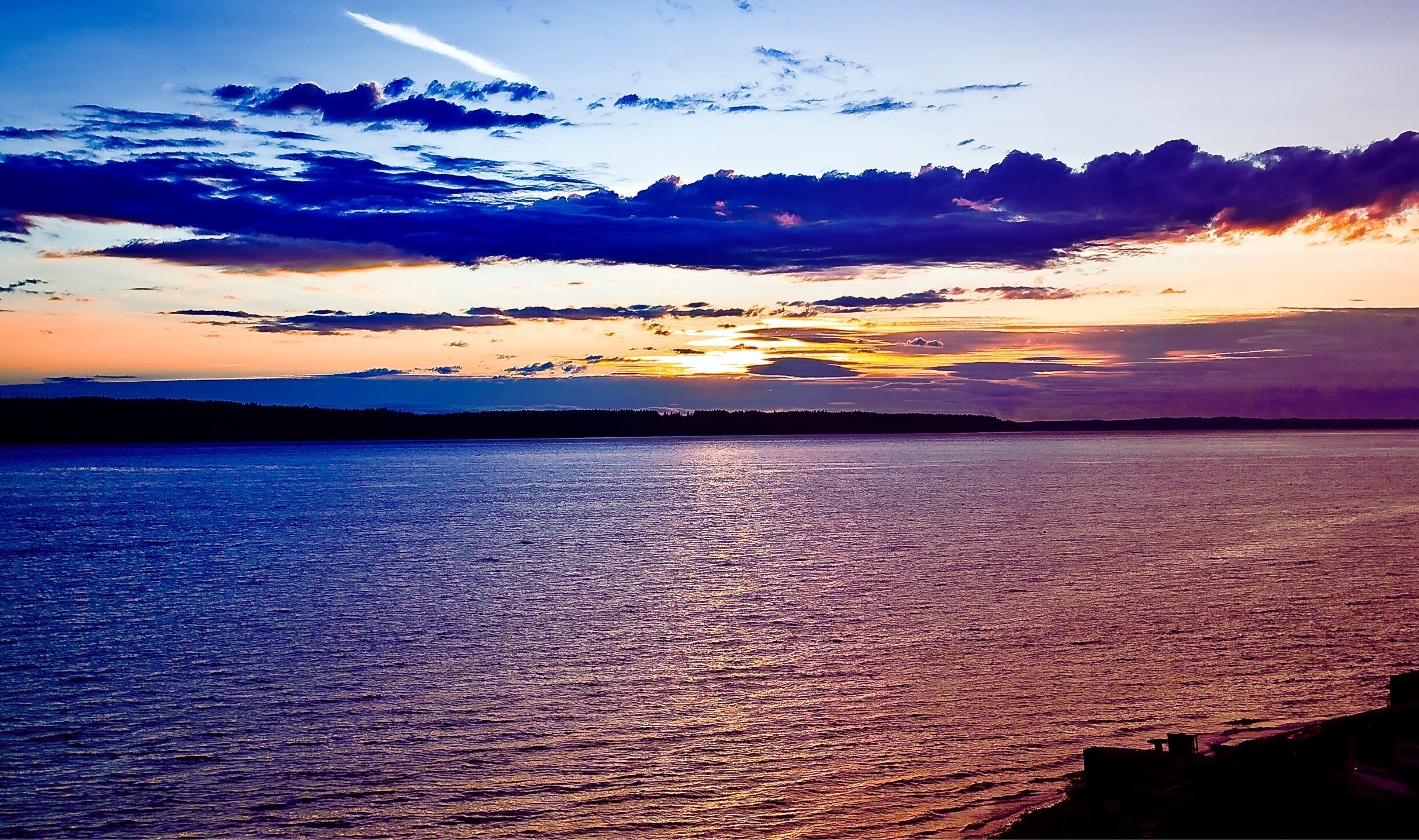Seattle's Puget Sound Sunset is often cloudy and rainy. This picture was taken on a rare sunny clear day. We look to the west and Whidbey Island from Camano Island Beach. 
There can be a summer beach in Seattle.   