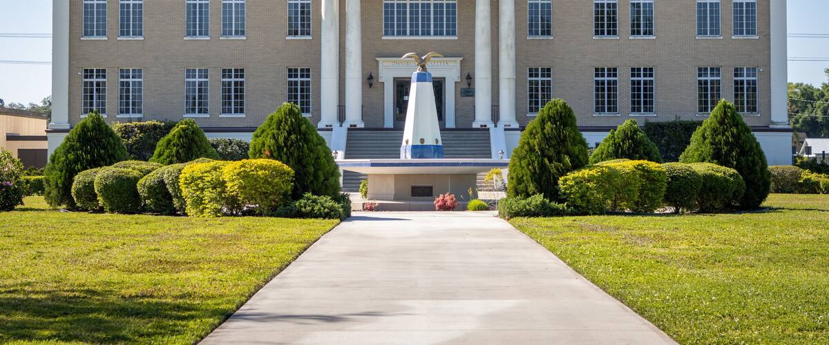 A large brick courthouse with a central entrance and a statue in front.
