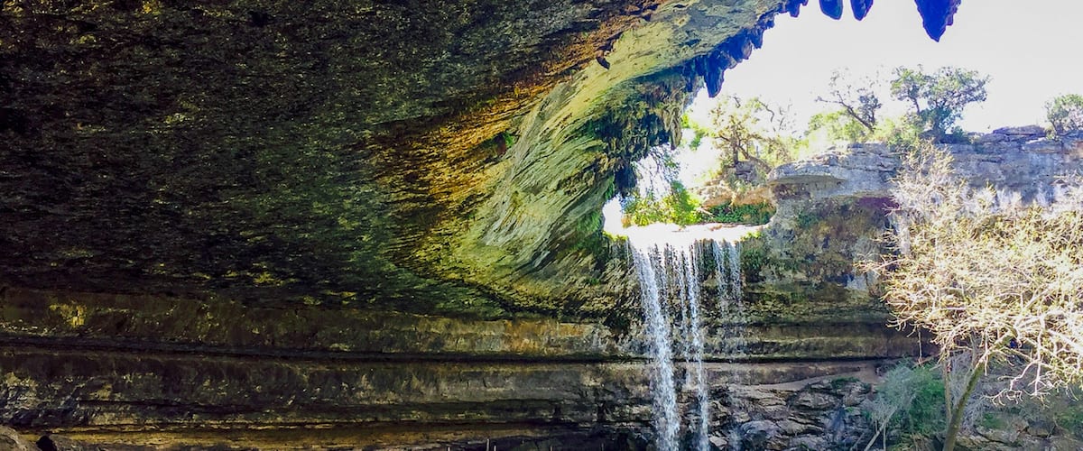 A cave with a waterfall and a pool of water.