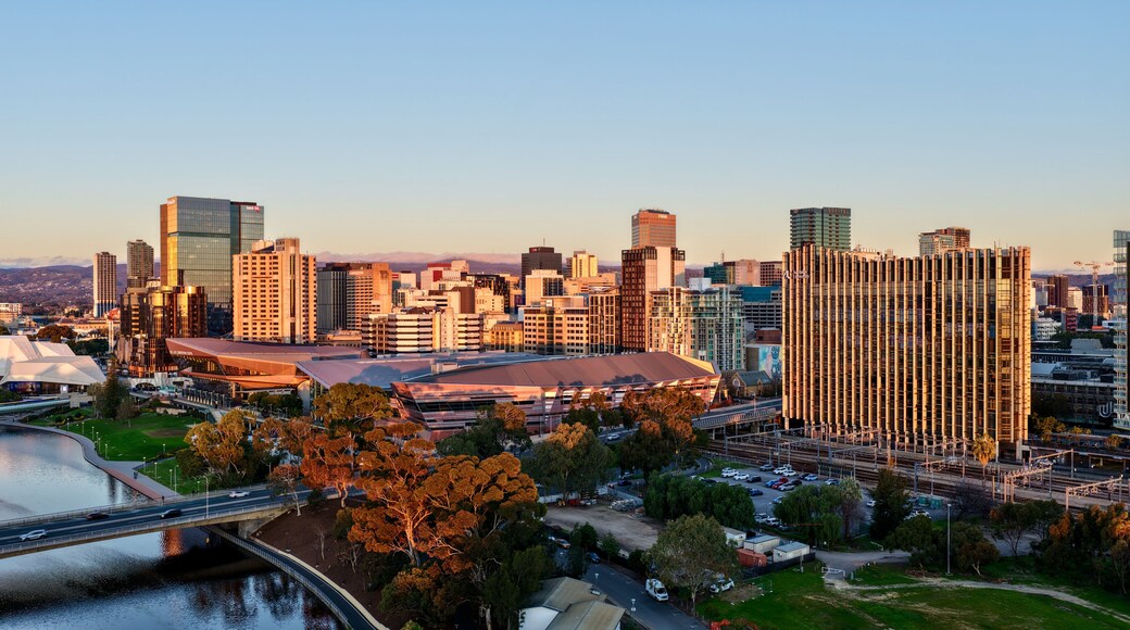 A city skyline with modern buildings, a stadium, and a river.