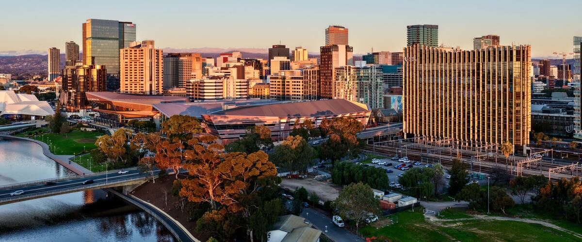 A city skyline with modern buildings, a stadium, and a river.