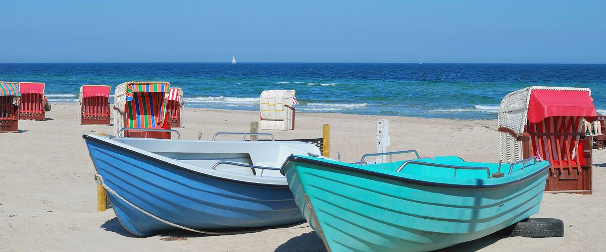 A beach with two boats and several beach chairs.