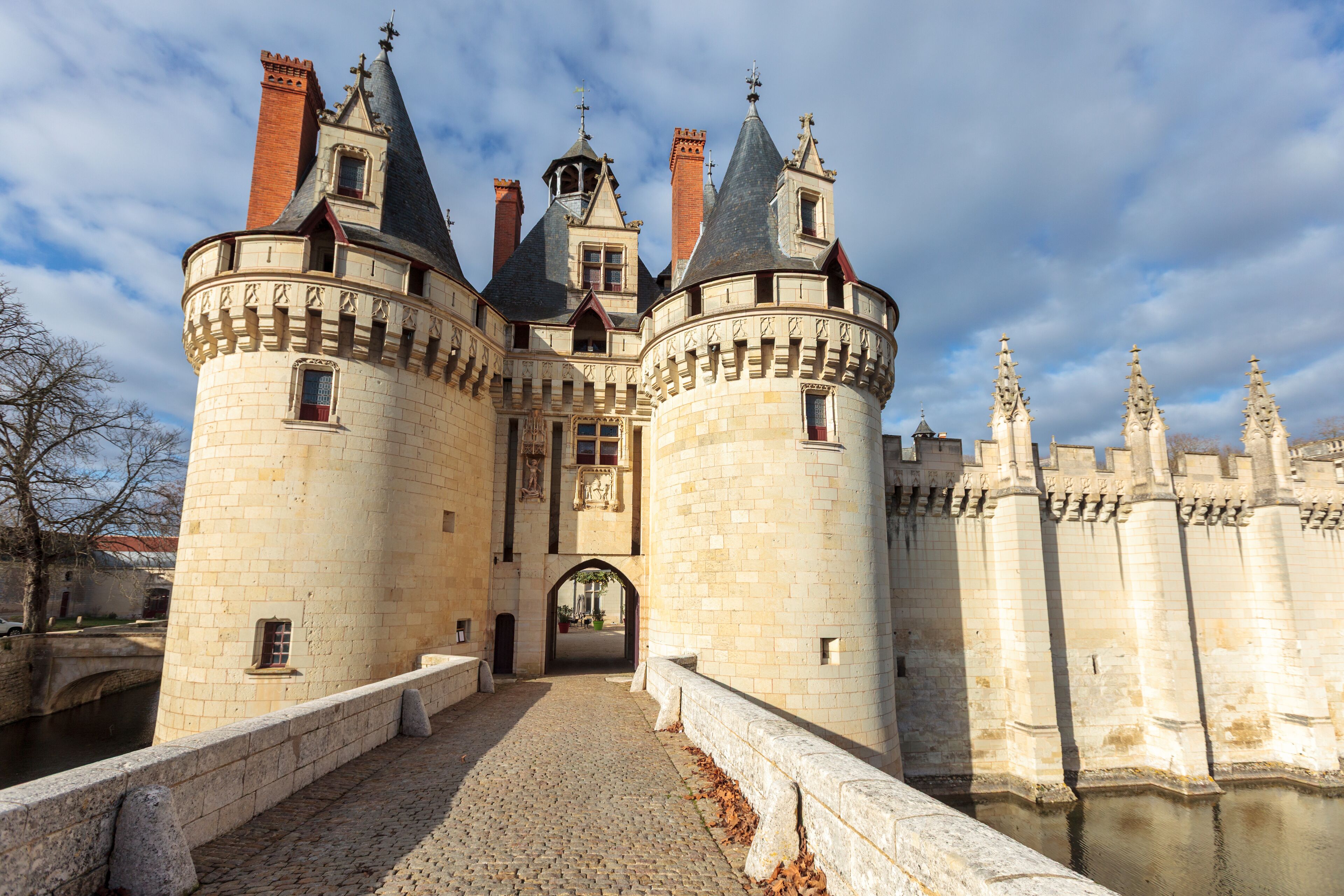 A historic castle with multiple towers, a moat, and a cobblestone pathway.