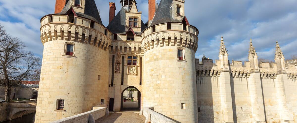 A historic castle with multiple towers, a moat, and a cobblestone pathway.