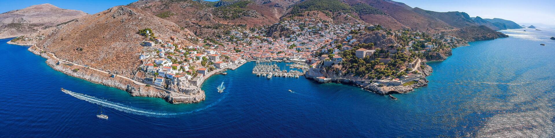 Aerial drone panoramic photo of the picturesque port and main village of Hydra (or Ydra) island at sunset. Hydra is a top tourist destination with neoclassic houses located in Saronic gulf, Greece.