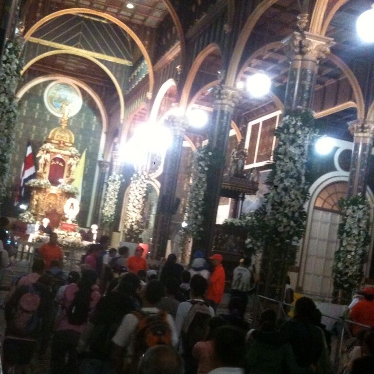 An ornate church interior with high arched ceilings, a central altar, and floral decorations.