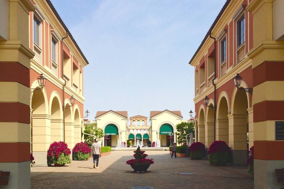 A courtyard with a central fountain, surrounded by buildings with arched windows and a clear sky.
