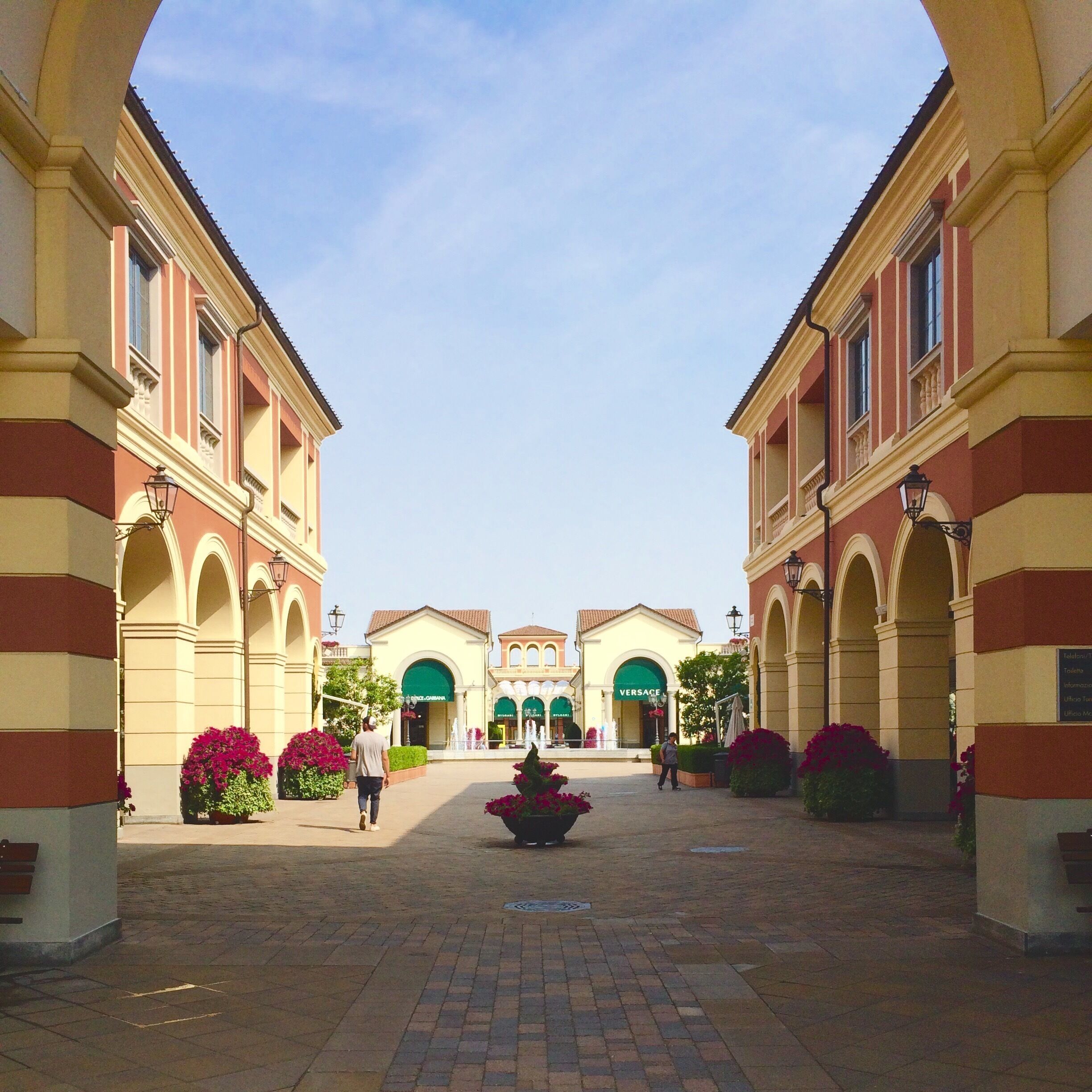 A courtyard with a central fountain, surrounded by buildings with arched windows and a clear sky.