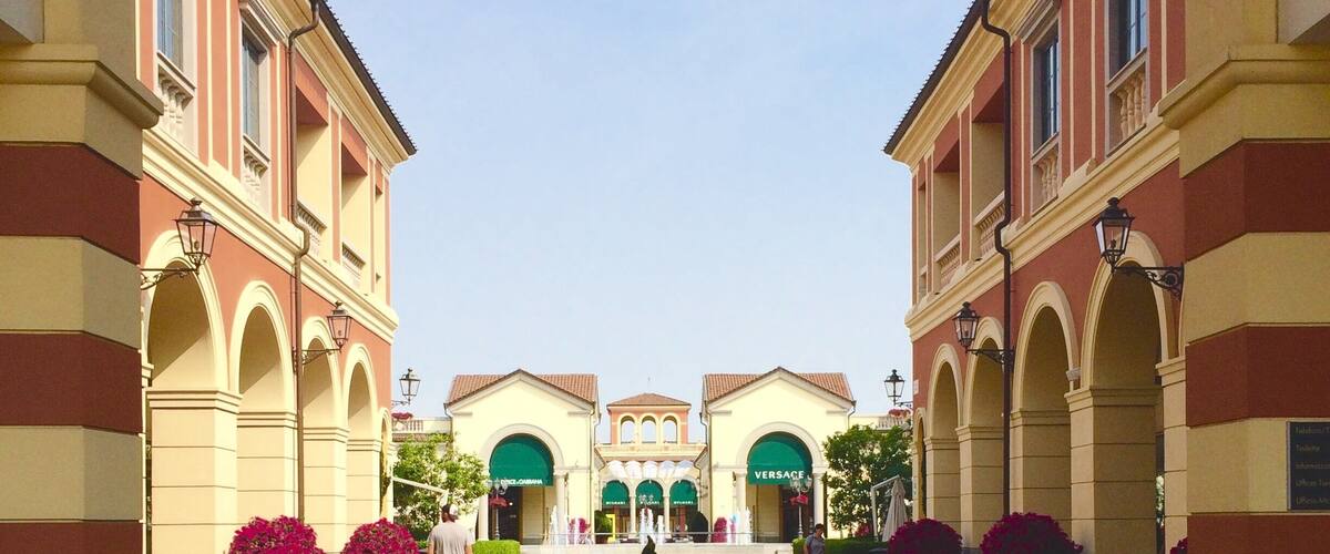 A courtyard with a central fountain, surrounded by buildings with arched windows and a clear sky.