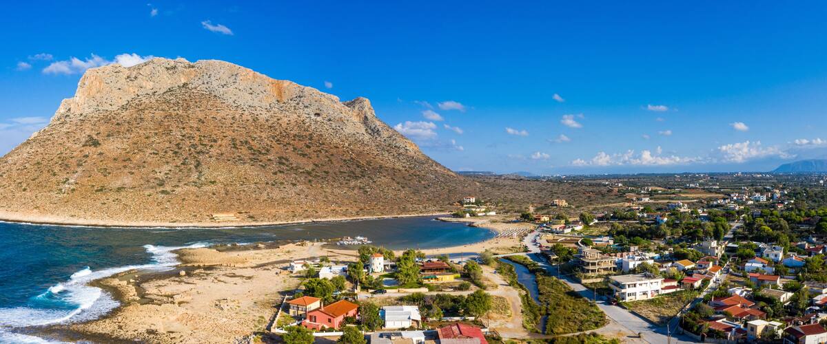 A coastal town with a prominent rocky hill, a beach, and residential buildings.