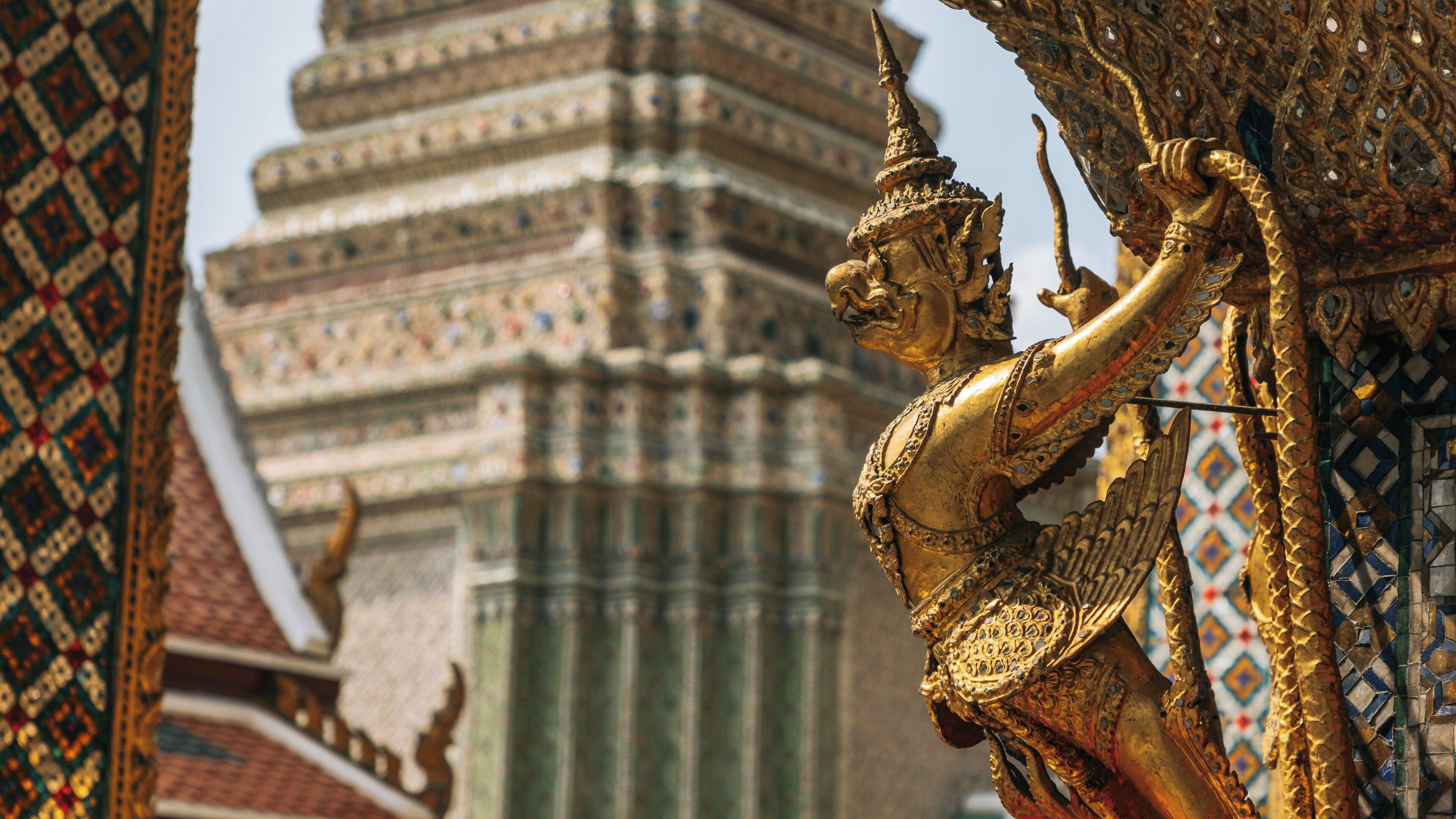 Golden guardian at Grand Palace in Bangkok showcasing intricate details of Thai architecture under bright sky