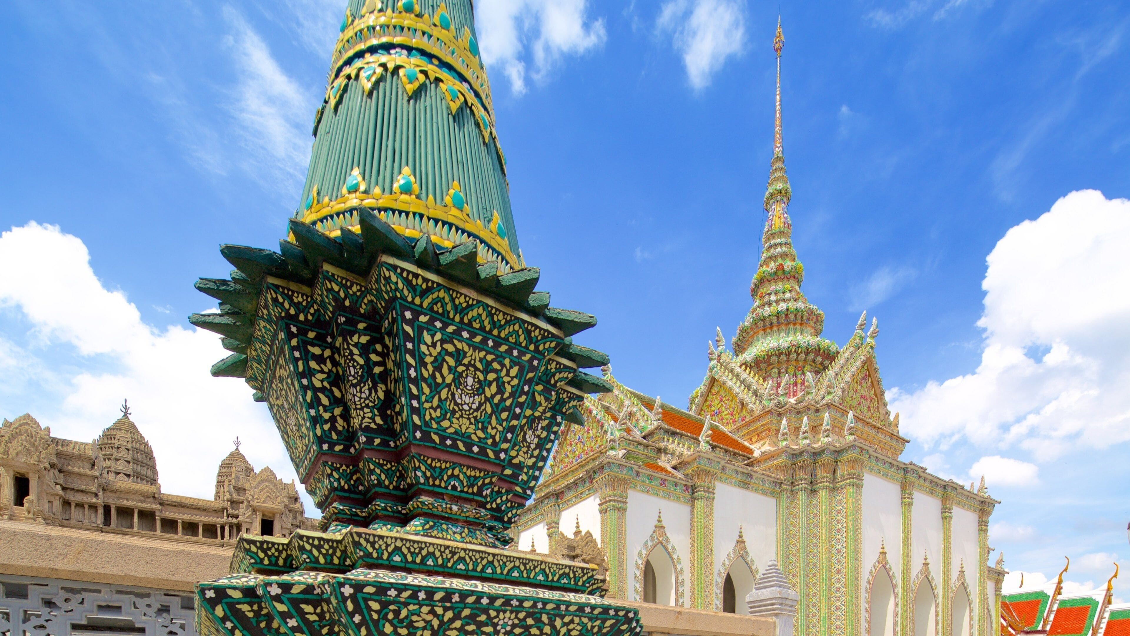 A temple with a tall spire and a large ornate structure in front.