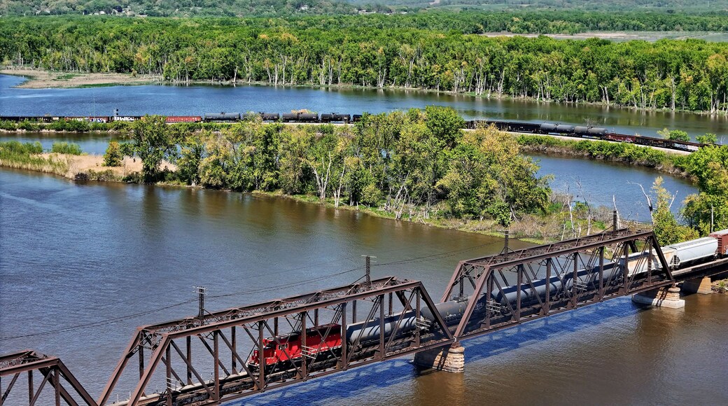 Aerial view of a Railroad locomotive pulling a freight train across the Mississippi river on a trestle bridge