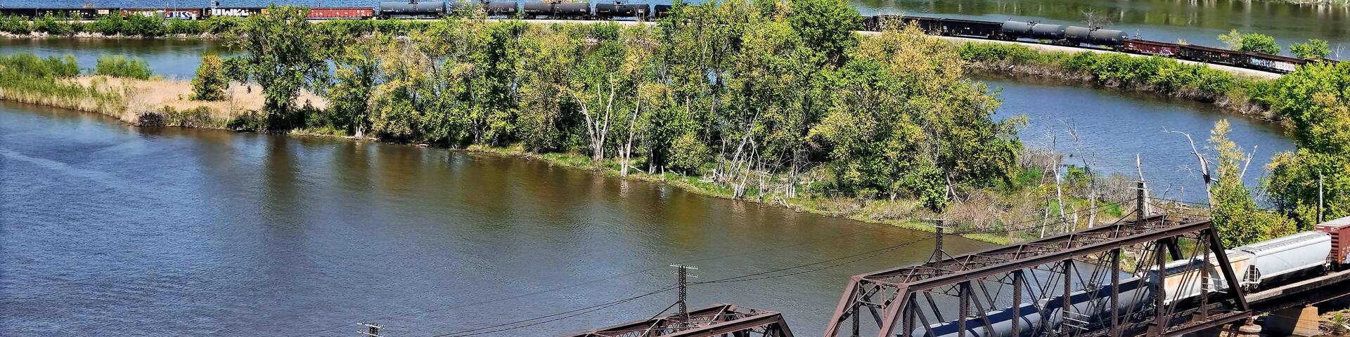 Aerial view of a Railroad locomotive pulling a freight train across the Mississippi river on a trestle bridge