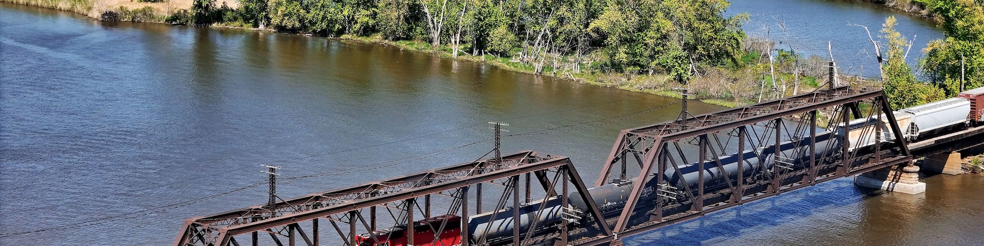Aerial view of a Railroad locomotive pulling a freight train across the Mississippi river on a trestle bridge