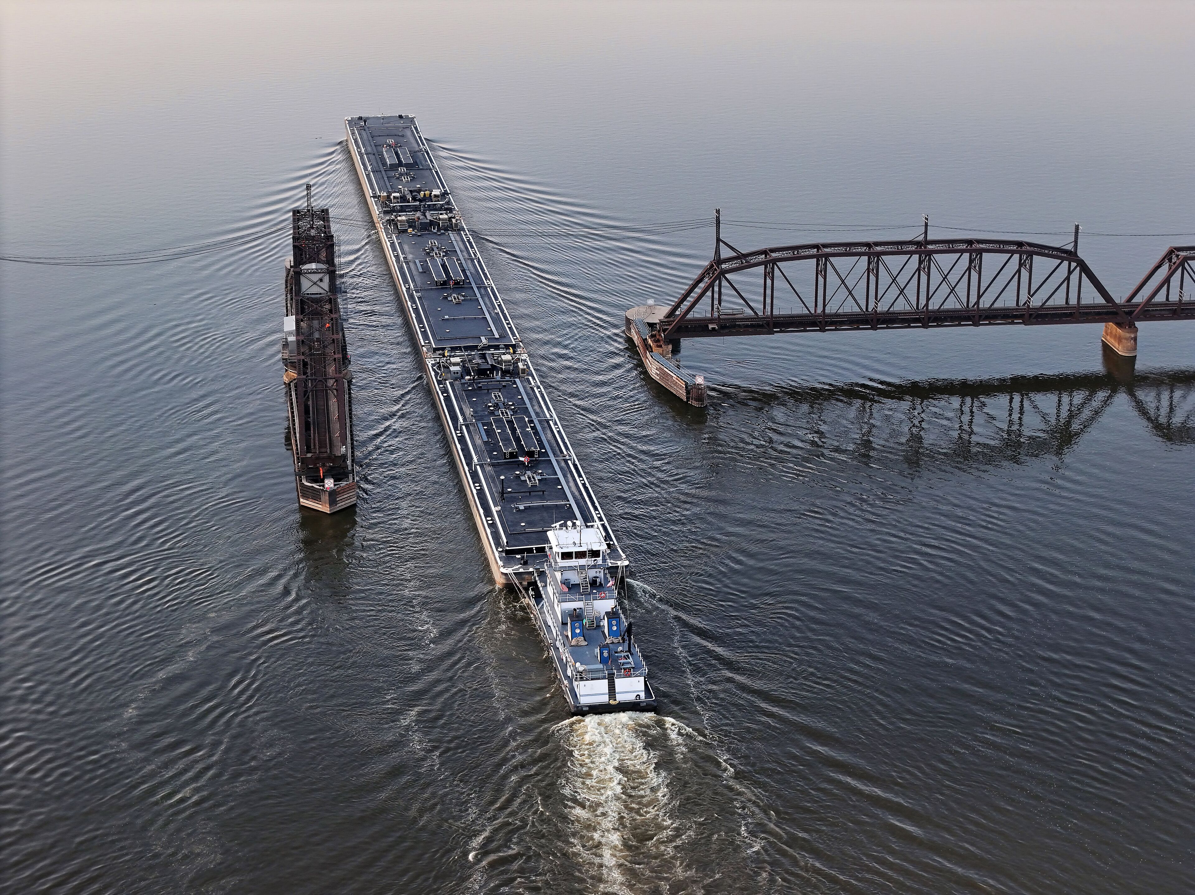 Set of liquid cargo barges being pushed through the narrow opening of the railroad swing bridge at Sabula Iowa