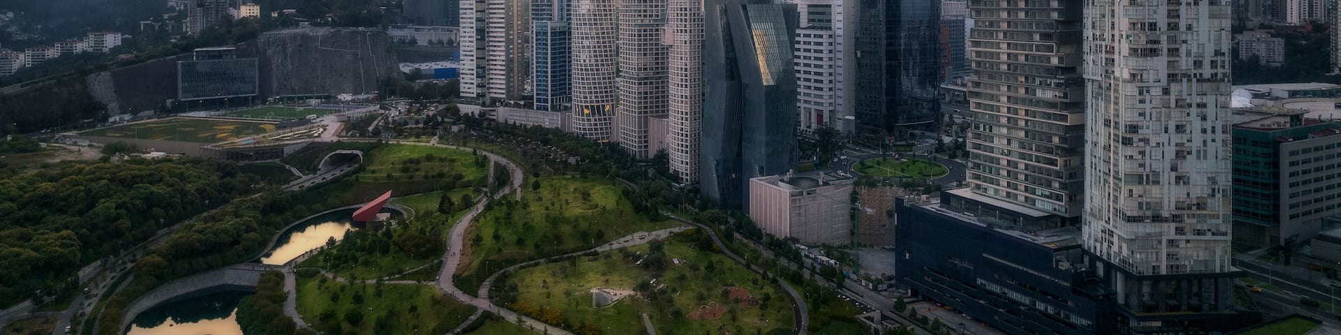 Aerial drone view of La Mexicana park in Santa Fe, a financial district in Mexico City, with skyscrapers at sunset, Mexico.