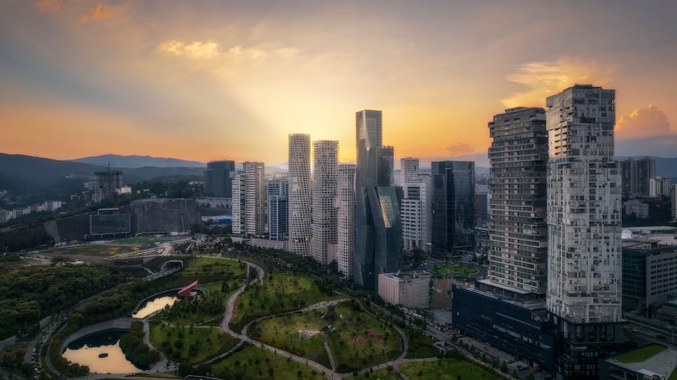 Aerial drone view of La Mexicana park in Santa Fe, a financial district in Mexico City, with skyscrapers at sunset, Mexico.