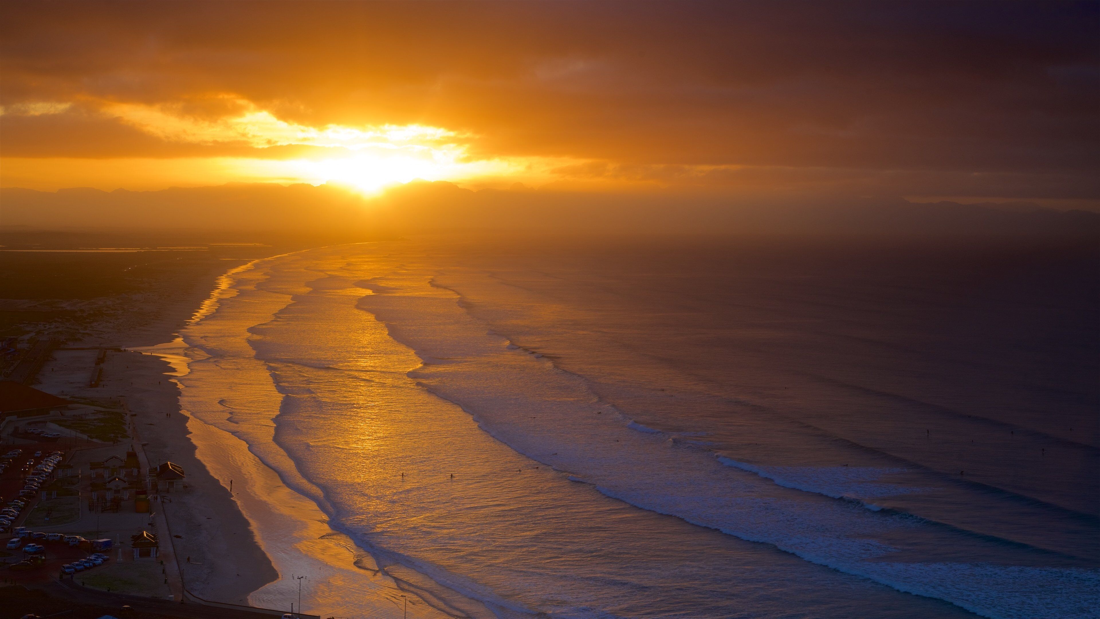 Muizenberg som inkluderer kyst, bølger og solnedgang