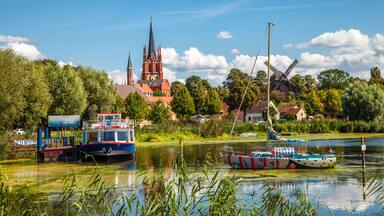 A river with boats, a church, and windmills.