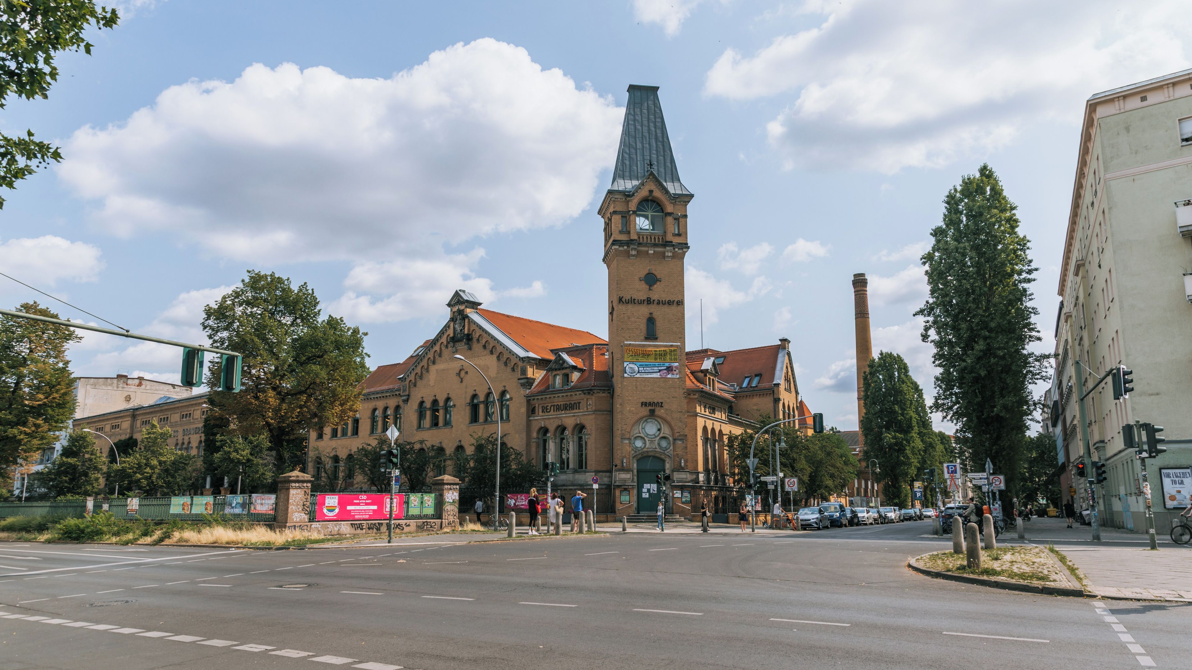 Ein historisches Gebäude mit einem markanten Turm, einem Restaurantschild und einem hohen Schornstein.