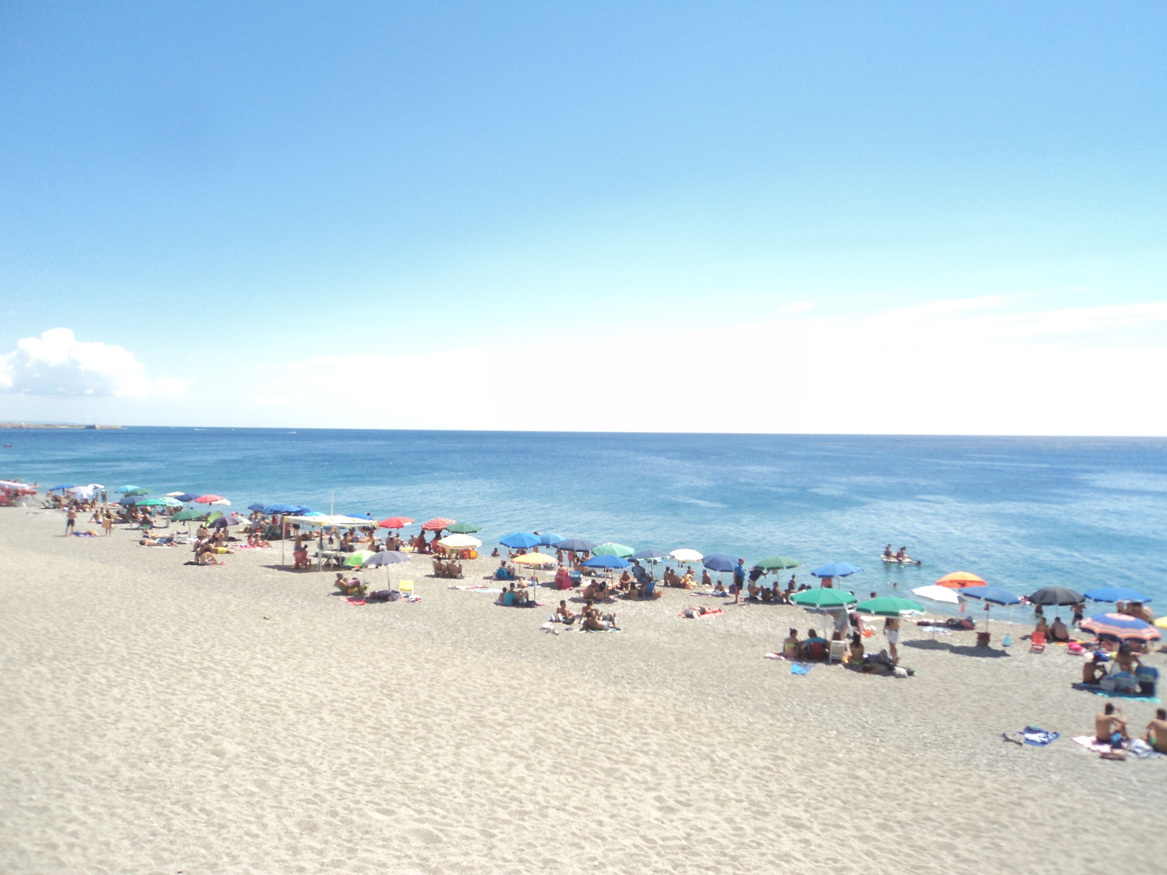 A beach with people relaxing under colorful umbrellas.