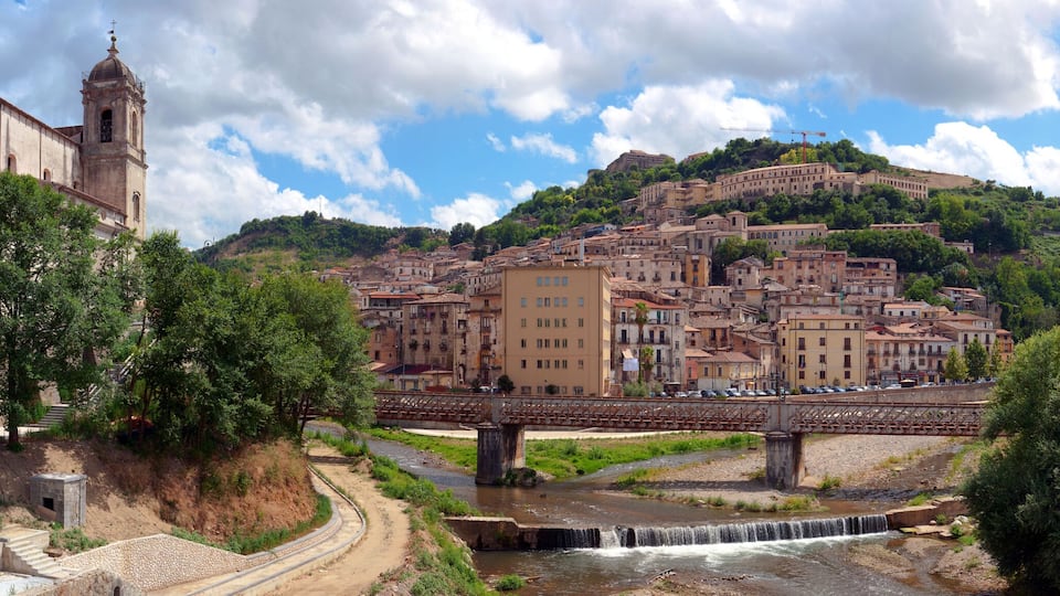 A historic town with a river, a bridge, and a hilltop church.